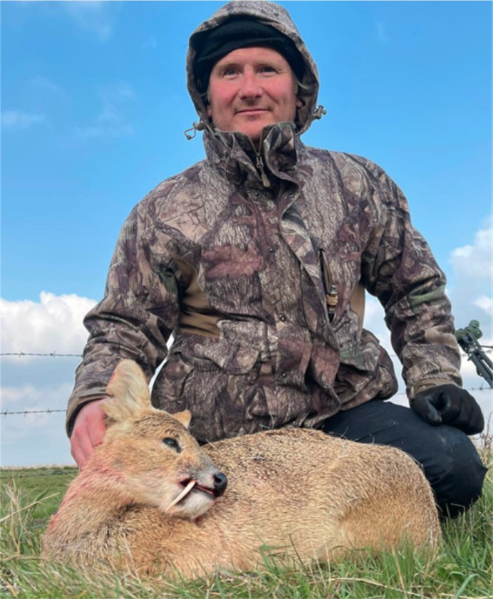 Camo-clad hunter with a Chinese water deer in the field