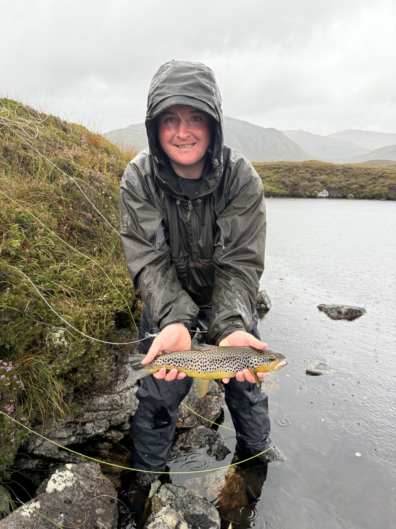 Angler with brown trout on a slate-grey day