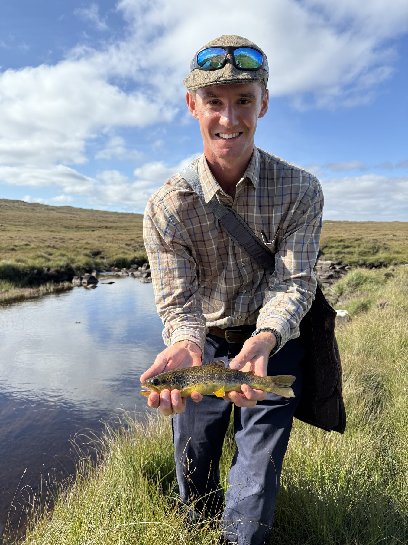 Angler with a brown trout on a sunny day