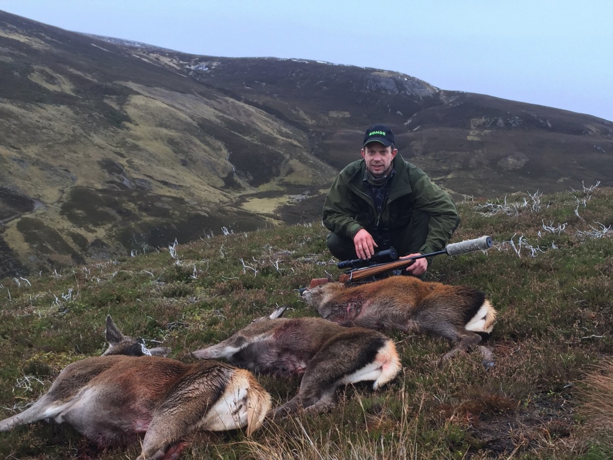Hunter with two hinds in the Highland glen