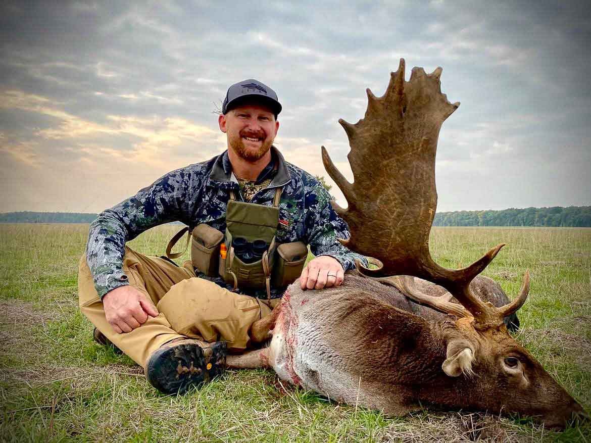 Hunter with a trophy Suffolk fallow buck at sunset
