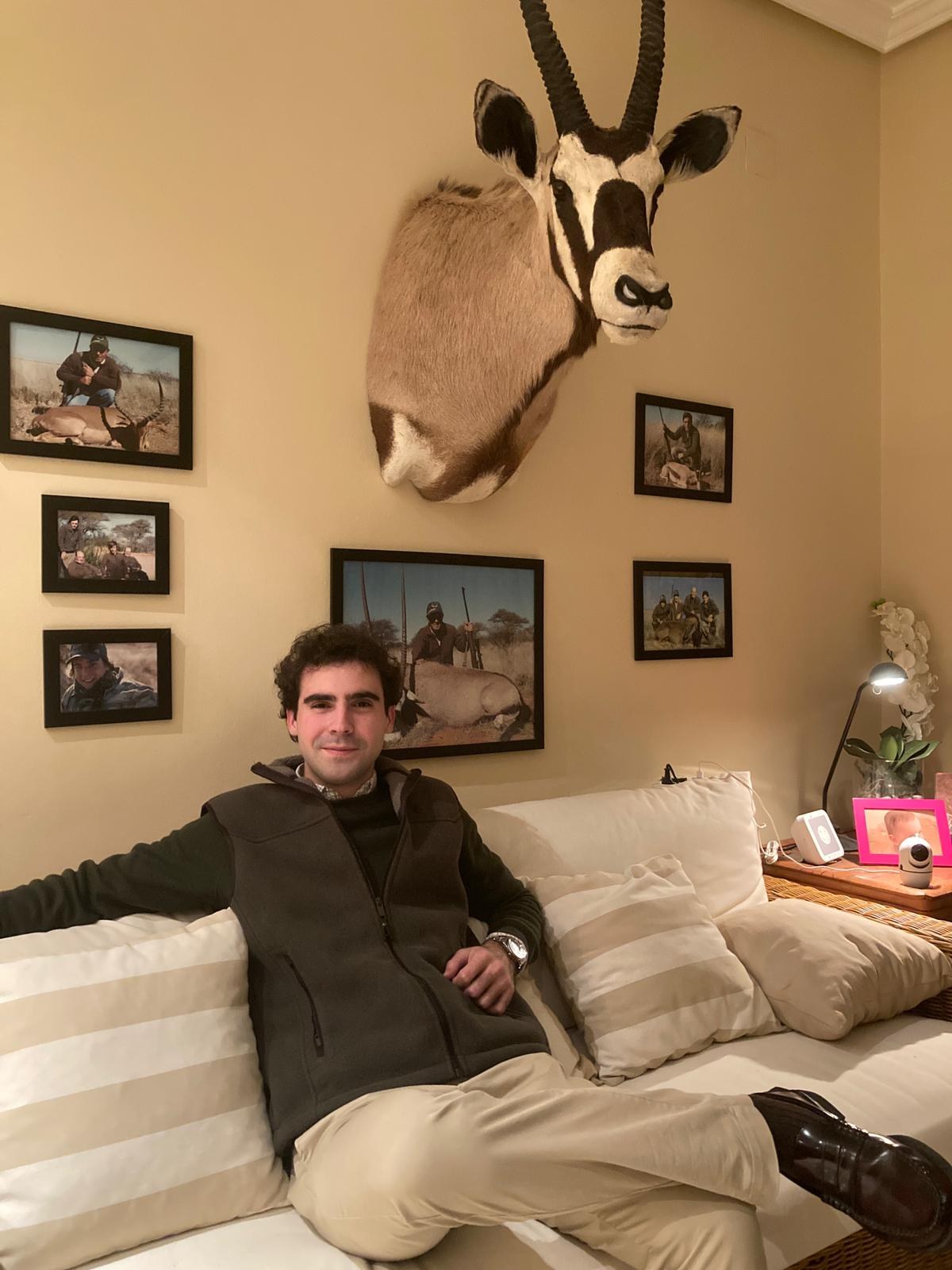Enrique at home with family hunting photographs and a gemsbok mount