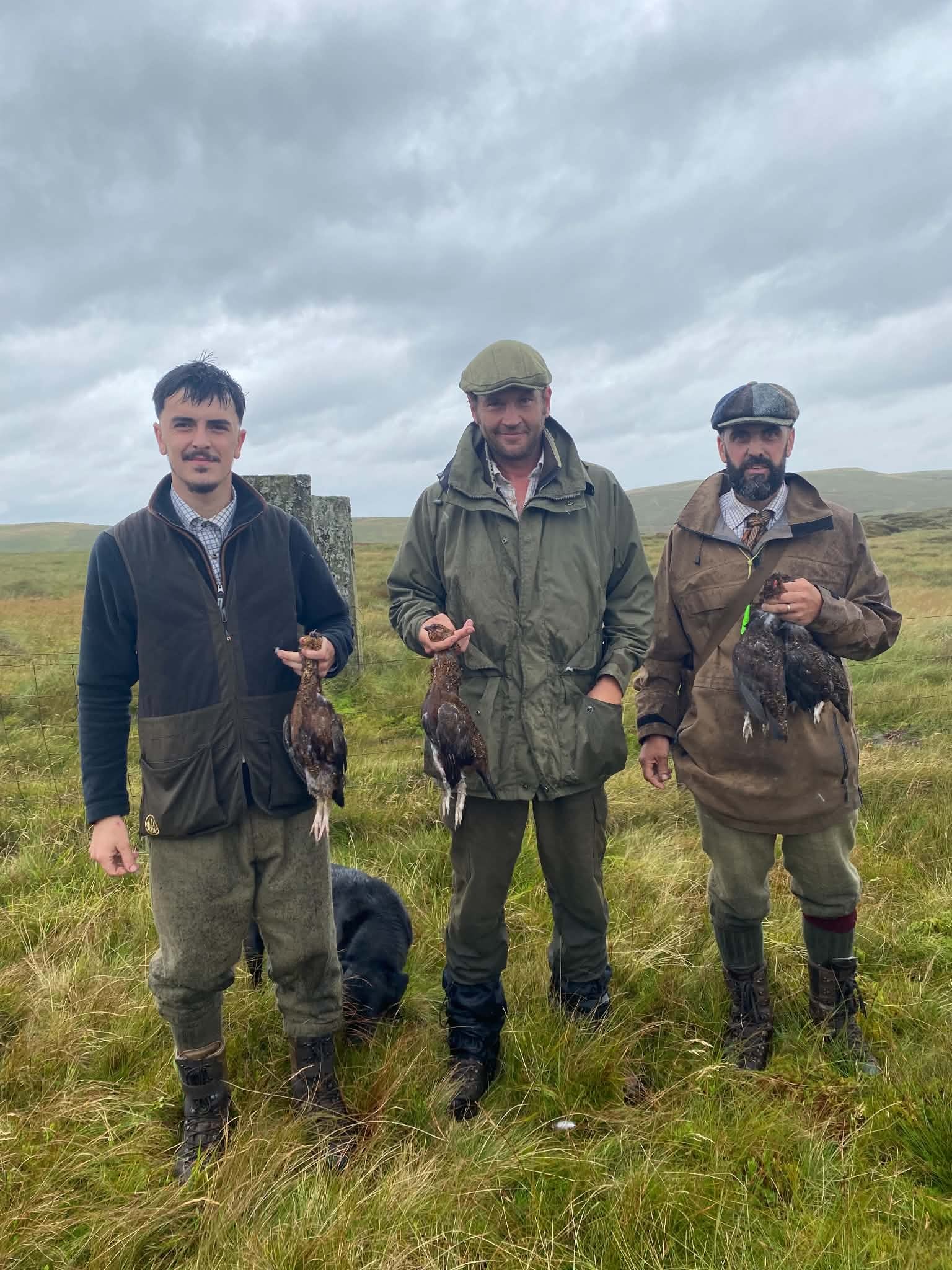 Three guns with grouse on an overcast moor